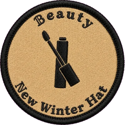 Embroidered Beauty patch — a mascara tube and wand stitched in black on camel